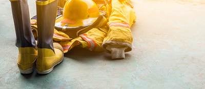 A yellow fireman’s uniform and boots laying on the ground. 
